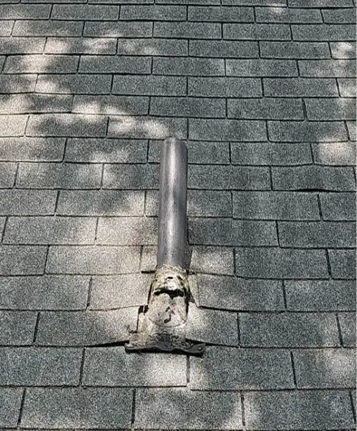 Gray shingled roof with a metal vent pipe and sealing around its base.