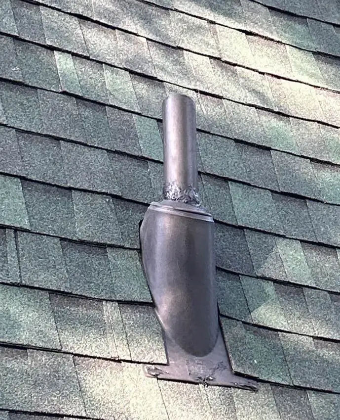 Metal vent pipe with flashing installed on a shingled roof section.
